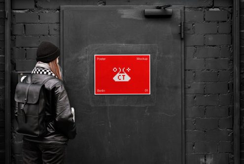 Person viewing a vibrant red poster mockup on a dark urban wall, ideal for designers looking to display graphic work in a realistic setting.